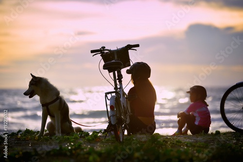 Mother ,Daughter and her dog Seat by the Sea with Bicycles .relaxing concept .