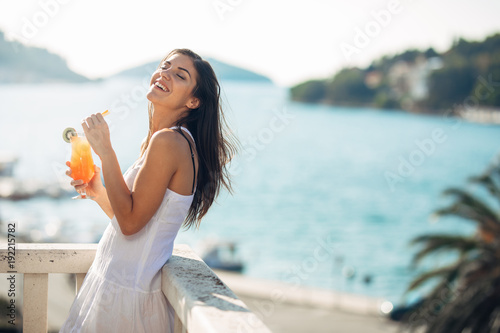 Carefree young female on holiday summer vacation having fun on a sunny day,relaxing with ocean view,listening waves,enjoying summer with refreshing drink.Love summer.Deserved vacation photo