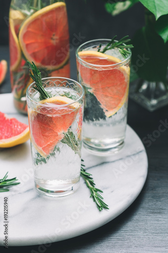 Cold detox cocktails with grapefruit and rosemary on a white marble serving tray.