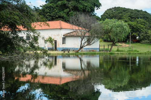 típica paisagem do interior do Brasil com um lago e uma casa ao fundo