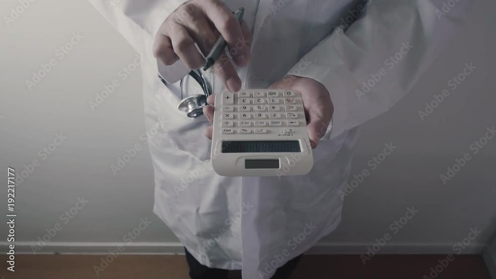 Healthcare costs and fees concept.Hand of smart doctor used a calculator for medical costs in modern hospital Healthcare costs and fees concept.Hand of smart doctor used a calculator for medical costs in modern hospital