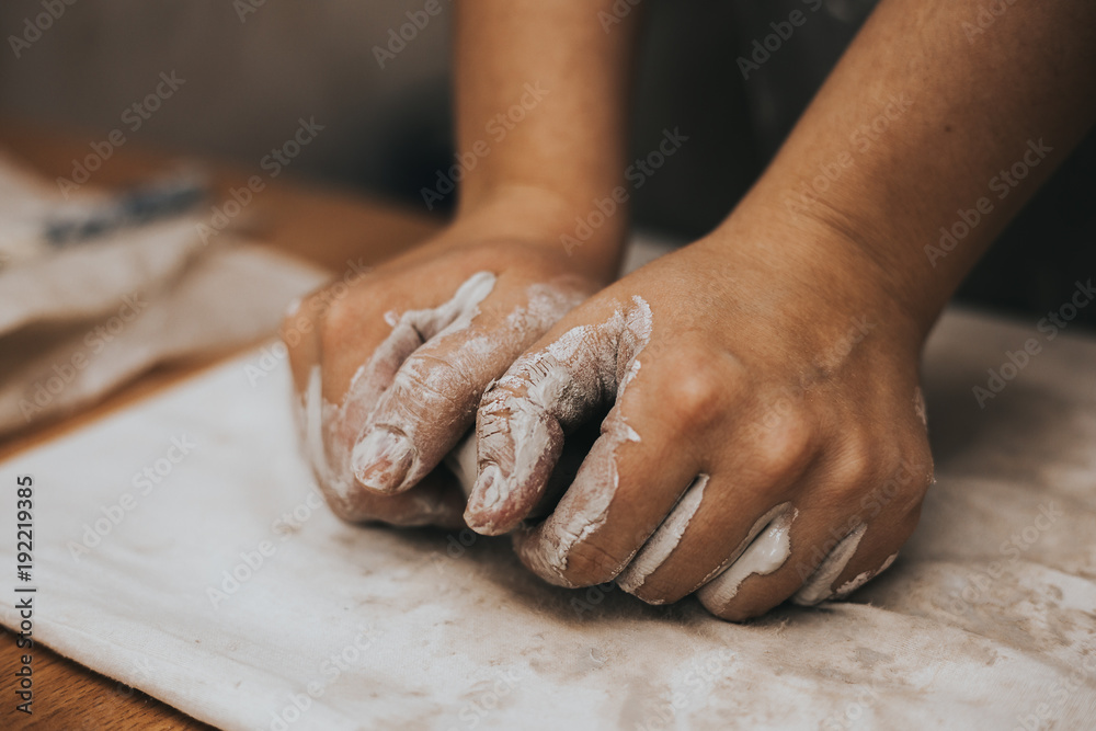 Female potter works with clay, craftsman hands close up, kneads and moistens the clay before work