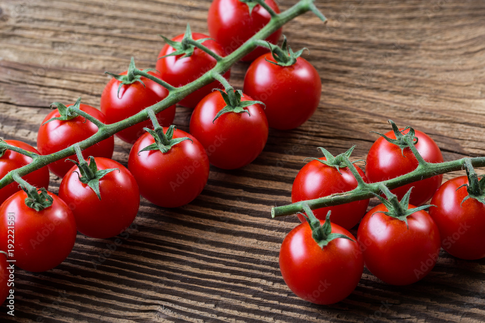 Fresh cherry tomatoes on a brown background. Bunch of fresh cherry tomato on a wooden table. Fresh cherry tomatoes on a brown background. Bunch of fresh cherry tomato on a wooden table.