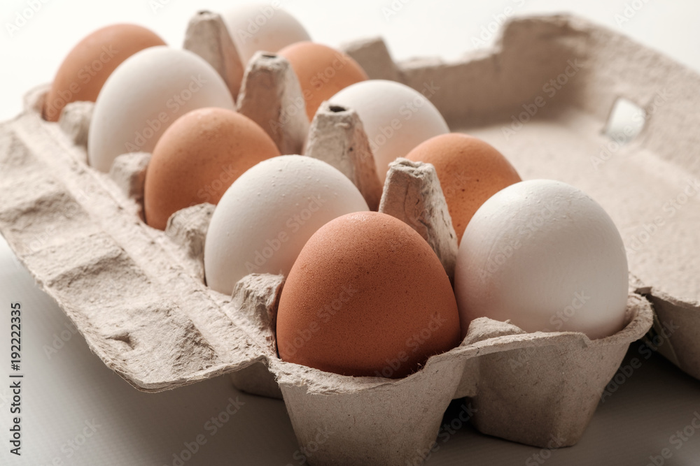 White and brown chicken eggs in a cardboard package.