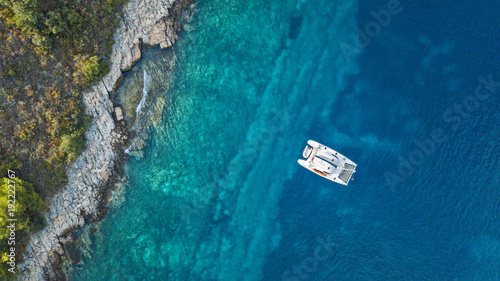 Fotografia, Obraz Aerial view of anchoring catamaran next to island.