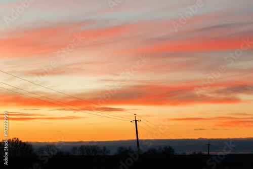 Silhouette of high voltage power lines against the background of dramatic sky at sunset.