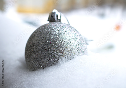 A large, shiny silver ball lies in the snow. Decoration for home and Christmas tree, close-up