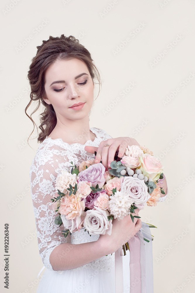 Beautiful girl holding a bouquet of flowers wearing in luxurious wedding dress isolated on background Beautiful girl holding a bouquet of flowers wearing in luxurious wedding dress isolated on background