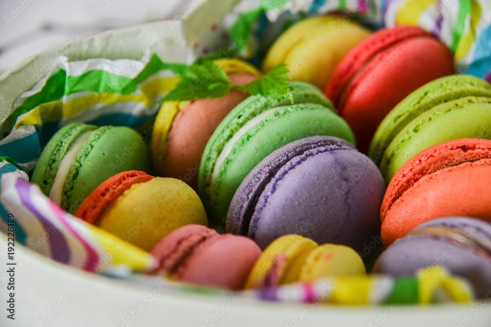 colorful macaroons in a gift box with a bright paper on a light background colorful macaroons in a gift box with a bright paper on a light background