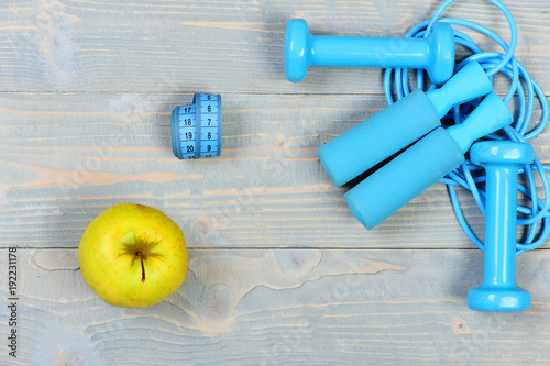 Gym tools, top view. Apple near barbells, centimeter, jump rope