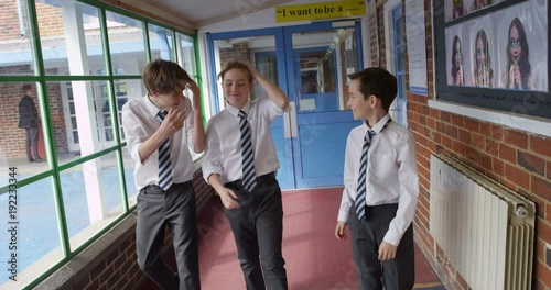 4K Happy young boys walking through school building laughing & teasing each other.