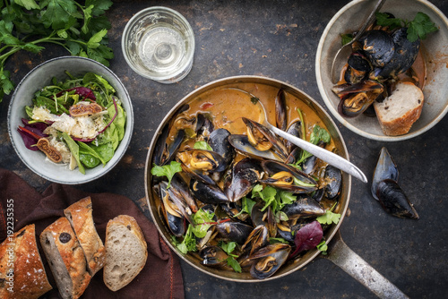 Traditional French blue mussel in bouillabaisse with lettuce and baguette as top view in a casserole