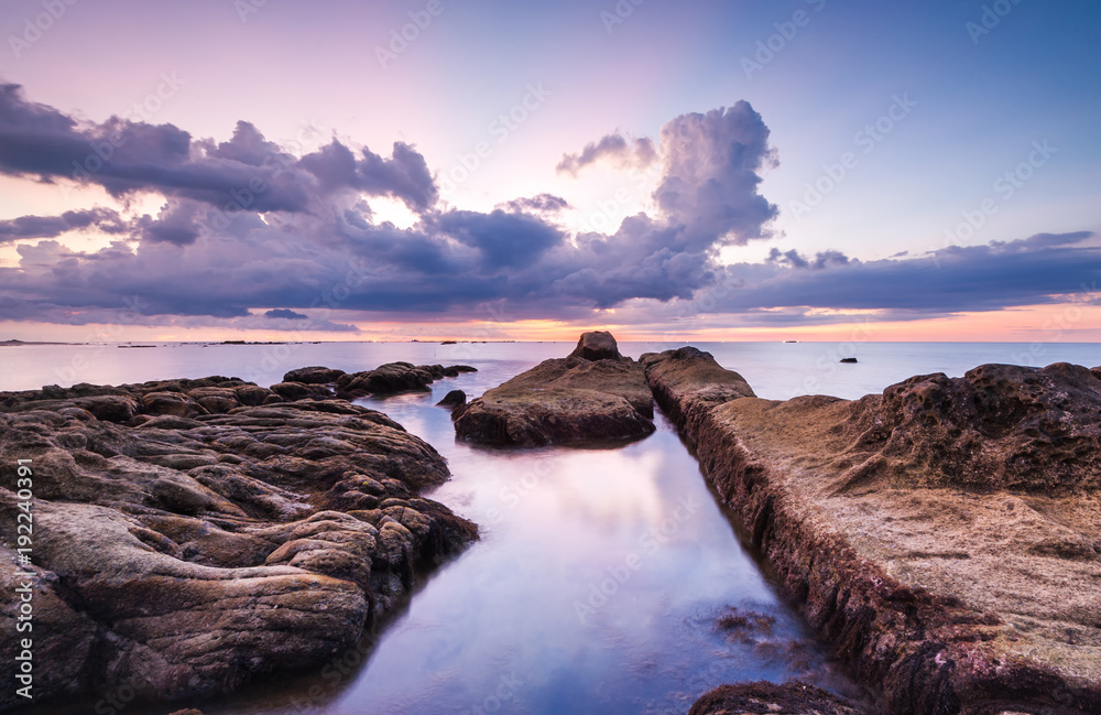 Sunset seascape with natural coastal rocks. Image contain soft focus due to long expose.