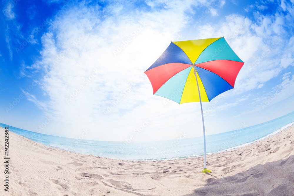 Opened multicolored sun umbrella on sand beach