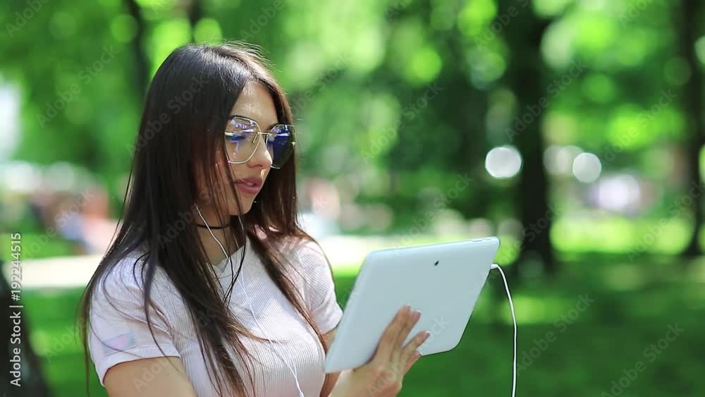Girl in glasses uses tablet pc. Beautiful woman with white tablet computer, female with tablet pc Girl in glasses uses tablet pc. Beautiful woman with white tablet computer, female with tablet pc