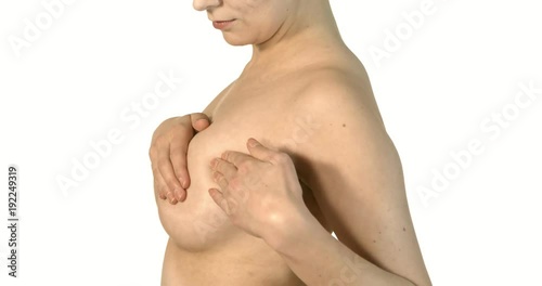 Close-up of young shirtless woman examining her breasts.