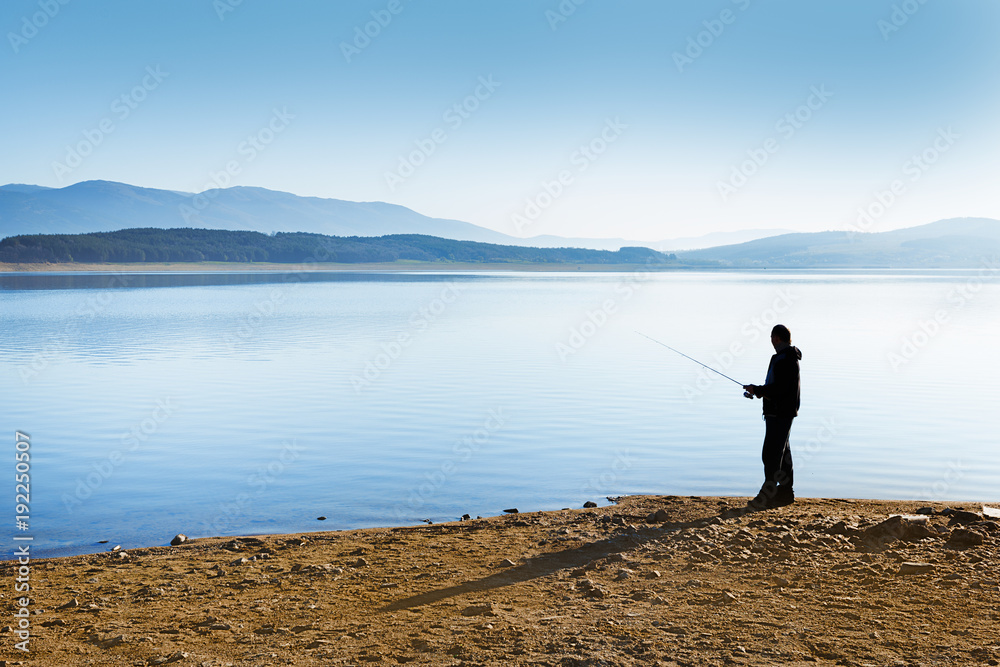 Fisherman silhouette at the background of beautiful sunset lake scenery in Bulgaria, Europe.