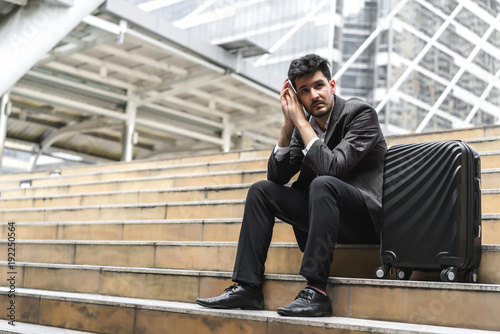 Business man sitting on stair with luggage in the routine of working with determination and confidence. concept of business trip travel and transportation. © bixpicture