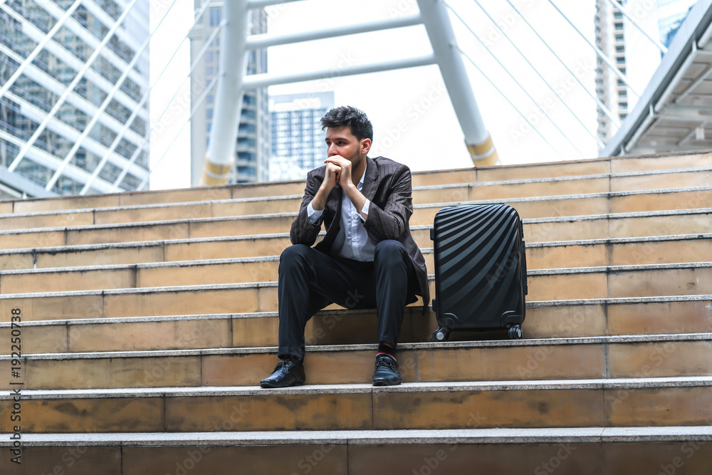 Business man sitting on stair with luggage in the routine of working with determination and confidence. concept of business trip travel and transportation. Business man sitting on stair with luggage in the routine of working with determination and confidence. concept of business trip travel and transportation.