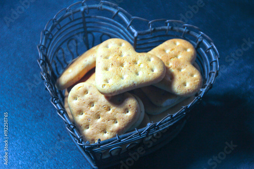 A heart cookie, in a vase in the shape of a heart on a dark background. A metal vase with cookies. Love.