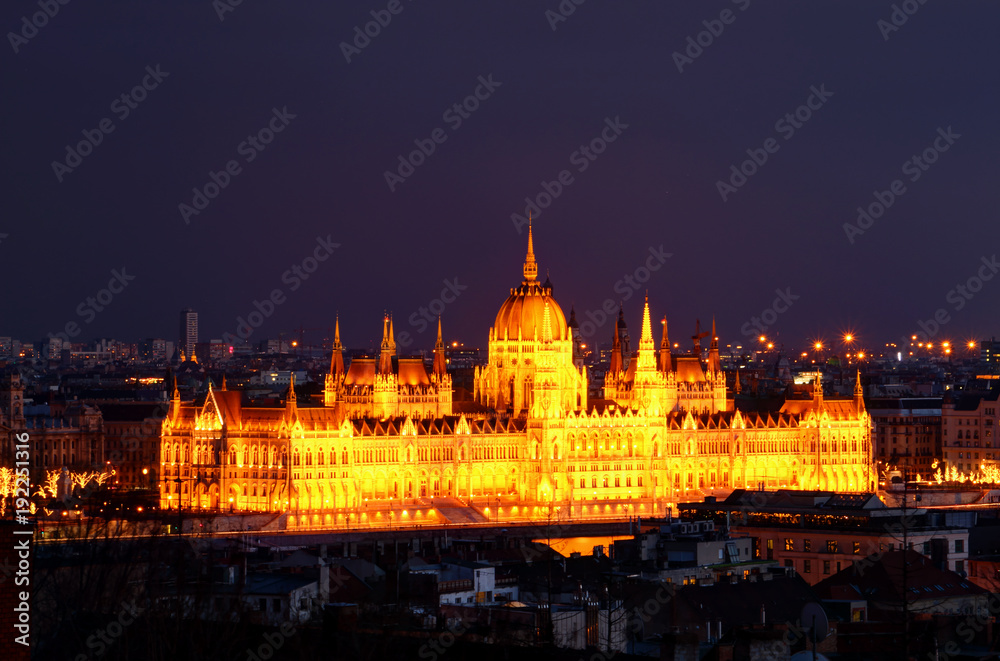 Panorama of Neo-Gothic Orszaghaz Parliament Building Hungarian legislative body seat at dusk illuminated by glowing yellow light on Danube riverbank Kossuth Square Pest Budapest Hungary Central Europe