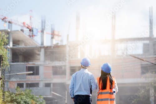 Fotografia Architects And Engineer at a construction site looking at blueprints and pointin