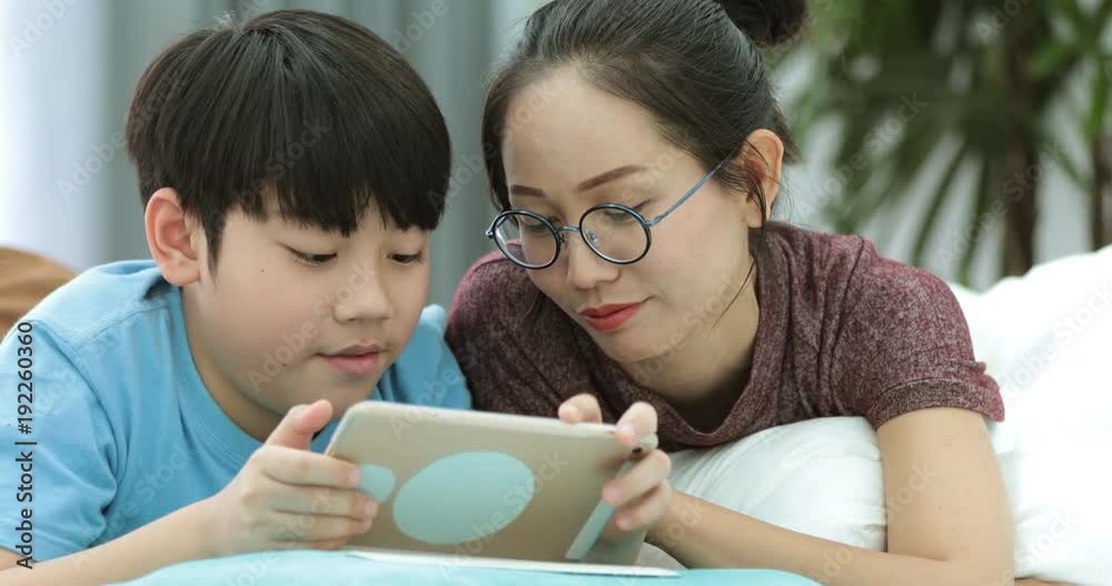 Young asian mother with son watching and playing tablet computer together at home. Young asian mother with son watching and playing tablet computer together at home.