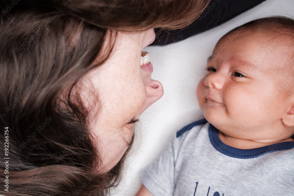Portrait of beautiful mum playing with her 3 months old baby in bedroom, top view, love mum concept Portrait of beautiful mum playing with her 3 months old baby in bedroom, top view, love mum concept