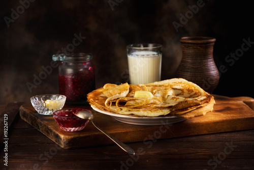 Pancakes with jam, butter and milk in a ceramic pot
