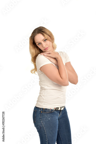3/4 portrait of blonde girl wearing white shirt, posing with hands touching body. isolated on white background.