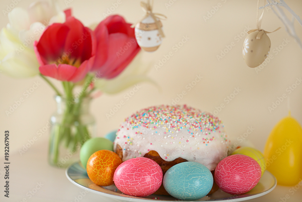 Easter cake with colored eggs,tulip flowers and twig with decorative Easter eggs on a beige background.Easter food. Easter composition. Easter cake with colored eggs,tulip flowers and twig with decorative Easter eggs on a beige background.Easter food. Easter composition.