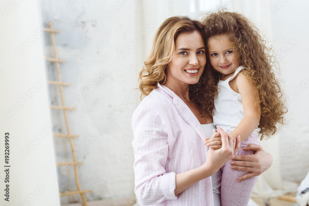 beautiful happy mother holding on arms her smiling curly daughter beautiful happy mother holding on arms her smiling curly daughter
