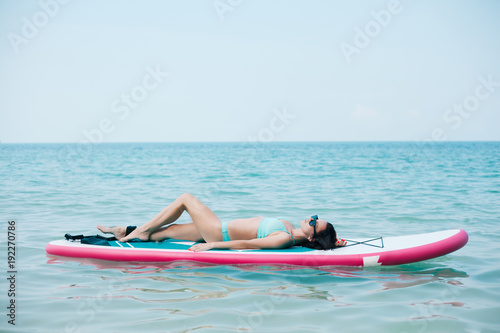 slim girl lying on paddle board on sea at tropical resort © LIGHTFIELD STUDIOS