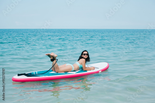 attractive slim girl lying on paddle board on sea at tropical resort © LIGHTFIELD STUDIOS