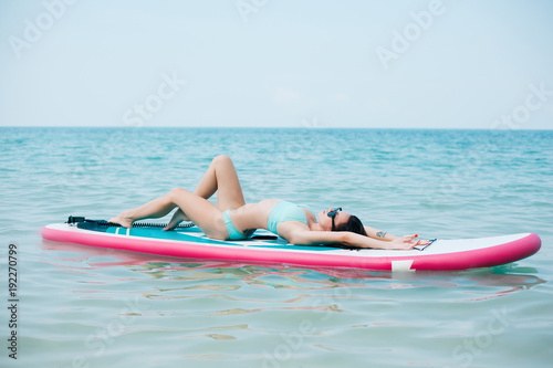 beautiful girl resting on paddle board on sea at tropical resort