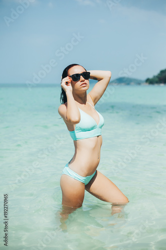 slim girl in swimsuit and sunglasses at tropical sea resort