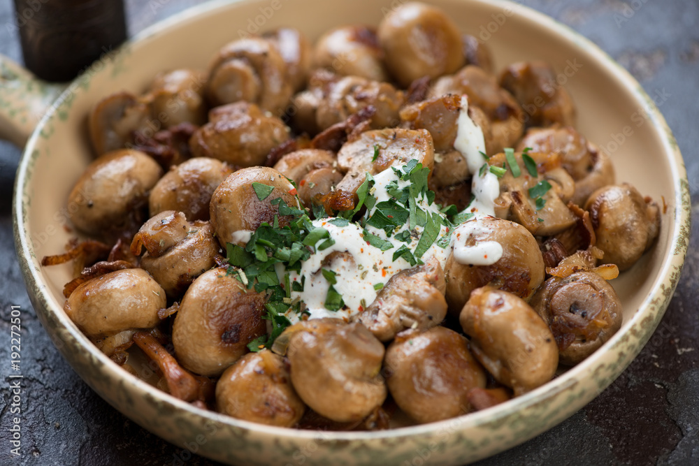Close-up of fried champignons and chanterelles with sour cream and fresh chopped parsley, selective focus Close-up of fried champignons and chanterelles with sour cream and fresh chopped parsley, selective focus