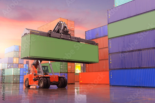 Картината върху платно Industrial background of container depot and reach stacker is working to carry green container during sunset beautiful sky