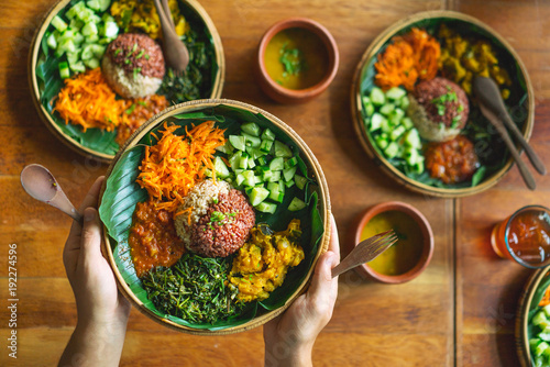 Vegetarian Indian food. Dish with rice, ogricami, spinach, carrots and sauce, on a sheet of banana tree in the hands of a man.