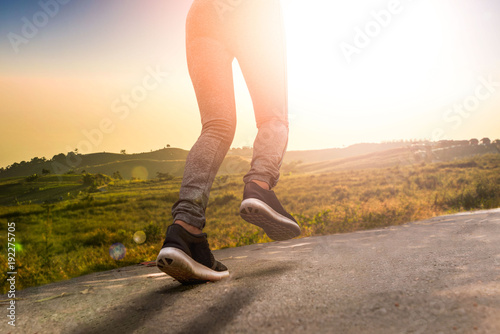 young fitness woman  running on road at sunset in nature
