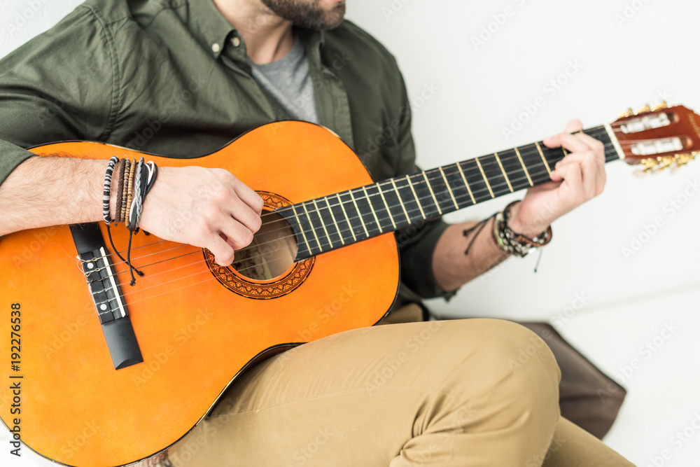 Obraz premium cropped image of man sitting and playing acoustic guitar