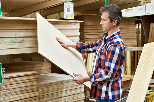 Man chooses plywood boards in store photo