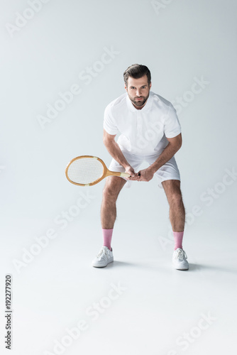 handsome tennis player with tennis racket on grey