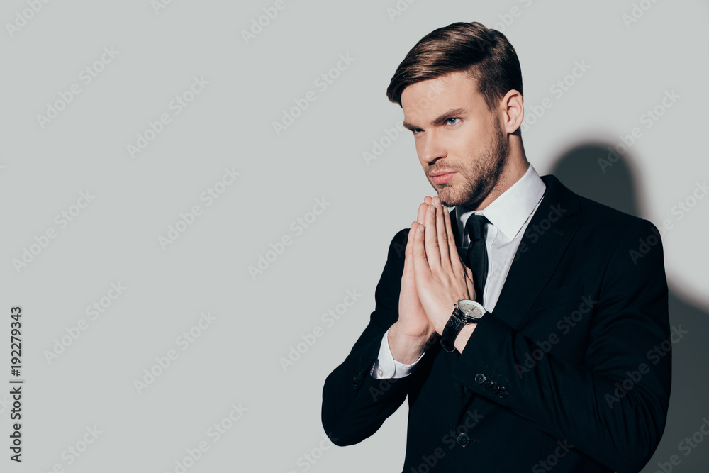Serious businessman in suit with pray gesture on white background Serious businessman in suit with pray gesture on white background