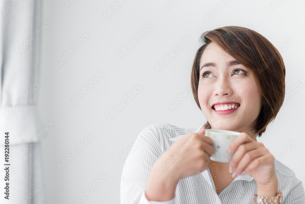 Happy young businesswoman drinking tea while sitting in chair at home Happy young businesswoman drinking tea while sitting in chair at home