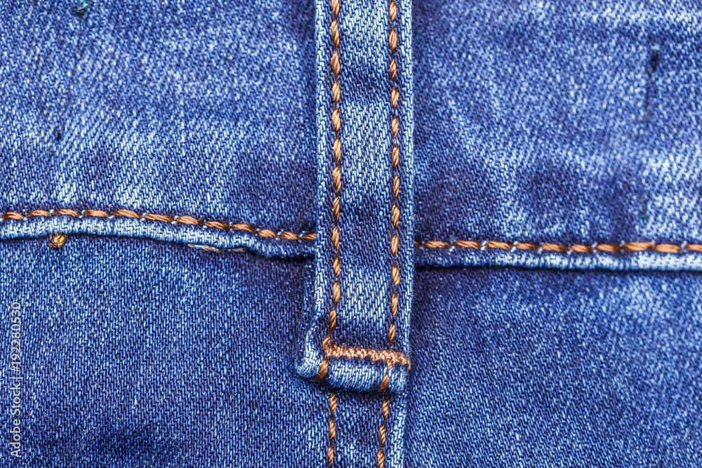 Close up image of a vibrant blue textured denim jeans with jeans texture along with a brown double stitching seam Close up image of a vibrant blue textured denim jeans with jeans texture along with a brown double stitching seam