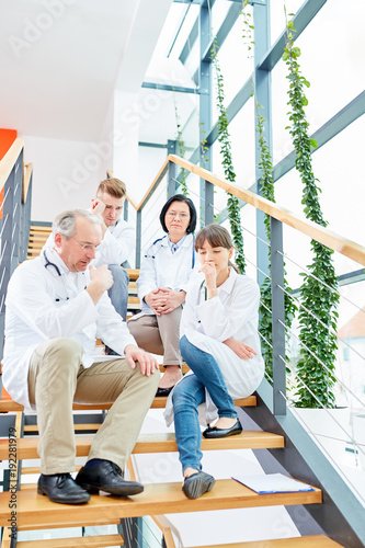 Ärzteteam sitzt auf einer Treppe im Krankenhaus