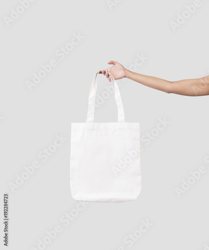 hand holding bag canvas fabric for mockup blank template isolated on gray background.