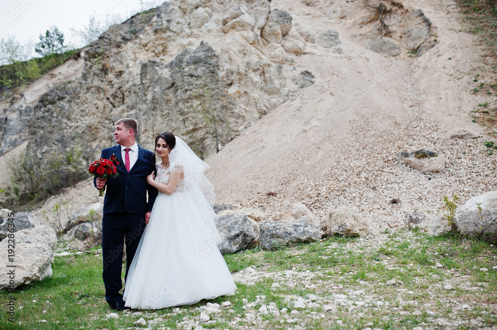 Romantic newly married couple posing and walking in rocky countryside on their wedding day. Romantic newly married couple posing and walking in rocky countryside on their wedding day.