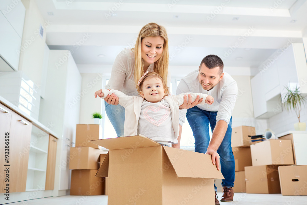 A happy family moves to a new apartment. Mother, father and child with boxes in the room of the new house. A happy family moves to a new apartment. Mother, father and child with boxes in the room of the new house.